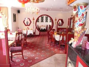 a dining room with tables and chairs and a chandelier at Beijing Dragon Hotel in Spilsby