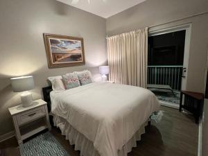 a bedroom with a white bed and a window at Lovely 3-bedroom beach condo! Walk to shop or eat! in Pensacola +33 photos