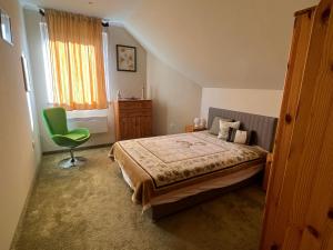 a bedroom with a bed and a green chair at Boldogfalvi apartman in Debrecen