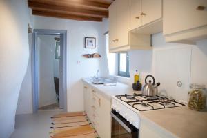 a white kitchen with a stove and a sink at Under The Linden Tree Tinos in Koumáros