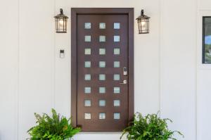 a brown door on a white house with two plants at Lakeside Haven in Gainesville