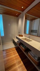 uma casa de banho com um lavatório e um espelho em Bangalô sobre o lago no Vale das Videiras em Petrópolis