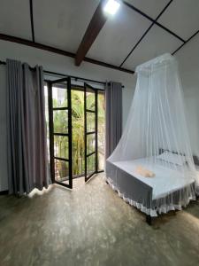 - une chambre avec un lit et une moustiquaire dans l'établissement Pearl Villa Rooms and Hostel, à Unawatuna