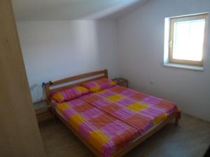ein Schlafzimmer mit einem Bett mit einer bunten Decke und einem Fenster in der Unterkunft Apartments Kujundžić in Kaprije