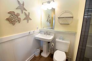 a bathroom with a sink and a toilet and a mirror at OCEANFRONT, Community Pool and beach walkway! KD220, Feelin Nauti in Kill Devil Hills +15 photos