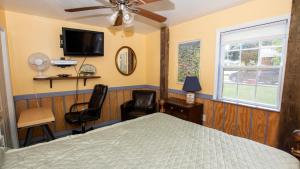 a bedroom with a bed and two chairs and a tv at Oceanside, Hot Tub, Close to beach, KD231, WindOver in Kill Devil Hills