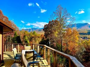 a deck with chairs and a table with a view of the mountains at Hawks View Gatlinburg Mountain Cabin in Gatlinburg