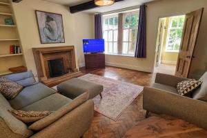 ein Wohnzimmer mit 2 Sofas und einem TV in der Unterkunft Spacious stone cottage w/ extensive private garden in Bolton