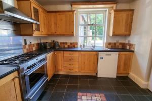 a kitchen with wooden cabinets and a stove top oven at Spacious stone cottage w/ extensive private garden in Bolton