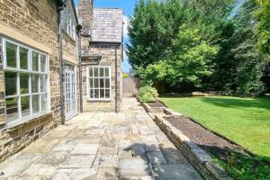 ein Backsteinhaus mit einem Gehweg, der zu einem Hof führt in der Unterkunft Spacious stone cottage w/ extensive private garden in Bolton