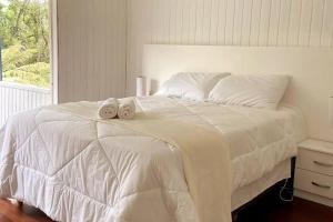 Un dormitorio con una cama blanca con toallas. en Blue House em Condomínio Fechado en Gramado