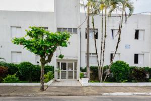 a white building with palm trees in front of it at Apto aconchegante com ar condicionado e wi-fi em rua tranquila in São Sebastião