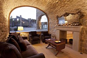 a living room with a fireplace and a stone wall at La Vella Farga Hotel in Lladurs
