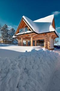 a pile of snow in front of a log cabin at Domki 4 Turnie in Ząb