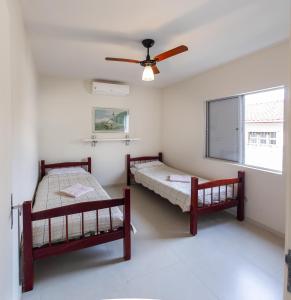 two beds in a room with a ceiling fan at Apto aconchegante com ar condicionado e wi-fi em rua tranquila in São Sebastião