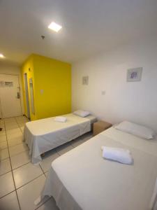 um quarto com duas camas e uma parede amarela em PRIME HOSPEDAGENS - Residencial Bellágio em São Luís