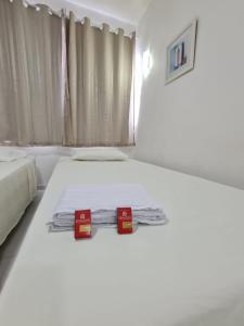 a white bedroom with two beds with red boxes on them at PRIME HOSPEDAGENS - Residencial Bellágio in São Luís