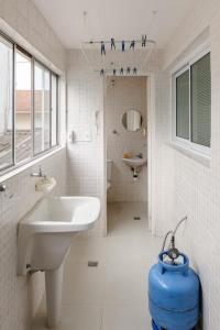 a bathroom with a white sink and a blue barrel at Apto aconchegante com ar condicionado e wi-fi em rua tranquila in São Sebastião