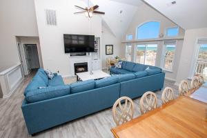 sala de estar con sofá azul y TV en BU70, Kings Landing- Oceanfront, Private Pool, Pool Table, Ocean Views, en Corolla