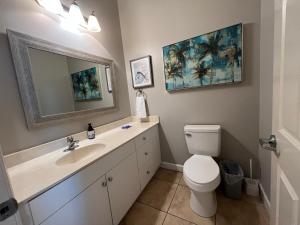 a bathroom with a toilet and a sink and a mirror at Lovely 3-bedroom beach condo! Walk to shop or eat! in Pensacola