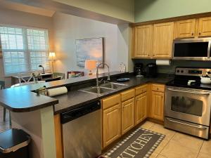 a kitchen with wooden cabinets and stainless steel appliances at Lovely 3-bedroom beach condo! Walk to shop or eat! in Pensacola