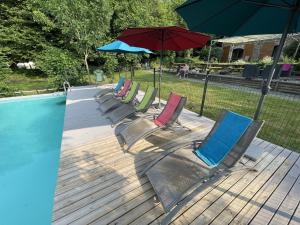 - une rangée de chaises et un parasol à côté de la piscine dans l'établissement Dordogne et Corrèze vacances - Gites, à Troche