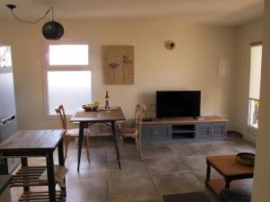 een woonkamer met een tafel en een televisie bij Bungalow LIDO-Playa Roca residence with sea front access - Free AC - Wifi in Costa Teguise