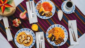 een tafel met borden ontbijtproducten en een kopje koffie bij Hotel Posada Stella Maris in Puerto Barrios