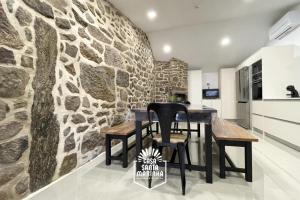 una pared de piedra en una cocina con mesa y sillas en Casa Santa Marinha, en Paredes de Coura