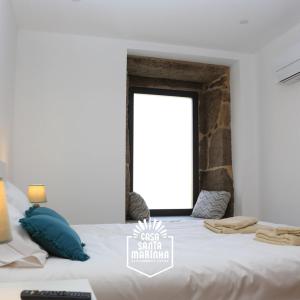a bedroom with a large white bed with a window at Casa Santa Marinha in Paredes de Coura