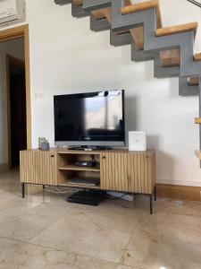 a television on a stand in a living room with stairs at 2 Bed Flat - Sleeps 6 - Pool - Garden - Parking in Milna