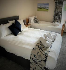 two beds in a hotel room with towels on them at The Marton Arms in Ingleton 