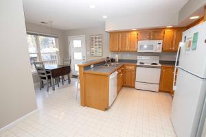 a kitchen with wooden cabinets and a white refrigerator at KD9, Sealoft- Soundside, Cozy, Close to Shopping and stores! in Kill Devil Hills
