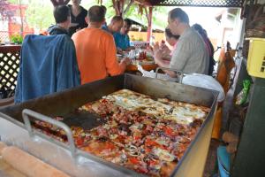 eine Gruppe von Menschen, die an einem Tisch mit einer großen Pizza sitzen in der Unterkunft Németh Tanya Vendégház in Pusztaszer