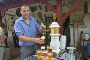 a man standing next to a table with glasses of beer at Németh Tanya Vendégház in Pusztaszer