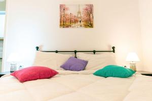 uma cama com três almofadas com uma pintura na parede em Maria's Apartment δίπλα στο Νοσοκομείο Παίδων και στο Λαϊκό em Atenas