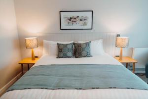 a bedroom with a white bed with two lamps at The Dunes in Tenby