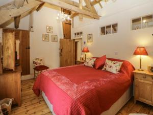 a bedroom with a bed with a red bedspread at The Miller's Cottage in Okehampton