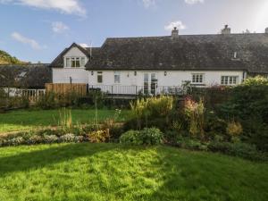 a white house with a garden in front of it at The Miller's Cottage in Okehampton