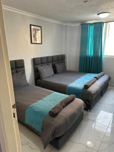 two beds in a room with blue curtains at ArwaHotel Apartments اروى للشقق الفندقية in Aqaba