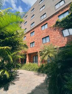 a red brick building with palm trees in front of it at Pauli Boutique Hotel in Fortaleza