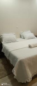 Cama blanca con sábanas y almohadas blancas en PagersHome Suites - Classic Nyarutarama en Kigali
