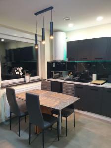 a kitchen with a table and chairs and a kitchen with black cabinets at Apart LILI in Polanica-Zdrój