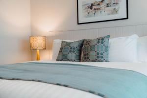 a bedroom with a white bed with pillows and a lamp at The Dunes in Tenby