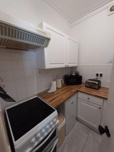 a kitchen with white cabinets and a stove top oven at Captivating 1-Bed Apartment in Blackpool in Blackpool