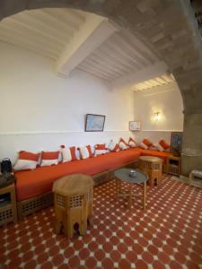 a living room with an orange couch and a table at Riad Darbask in Essaouira