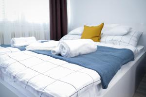 Una cama blanca con toallas y almohadas. en Villa Blue Arany Apartman, en Szekszárd