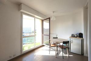 cocina con mesa y sillas y ventana grande en Special Loft : 40 m² de confort, en Cergy