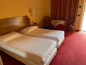 a hotel room with two beds and a table at Hotel Don Carlo in Broni