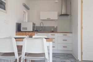 a kitchen with white chairs and a wooden table at Come à la maison! in Coupvray